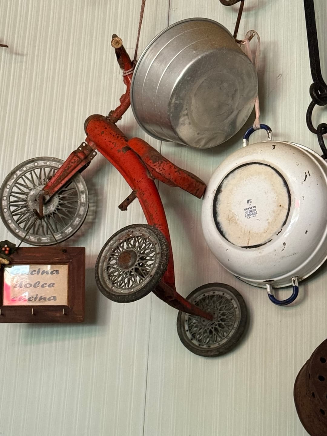 A childhood bicycle and old kitchenware hanging on the wall