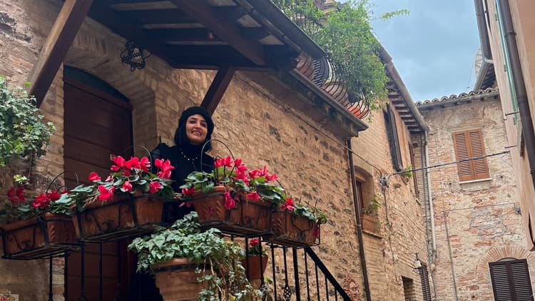 A flower-decorated balcony and doorway in a stone lane in Spello, Umbria