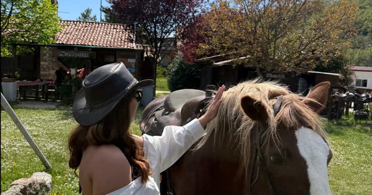 A horse at an Umbrian farm holding a paper map as a traveler laughs